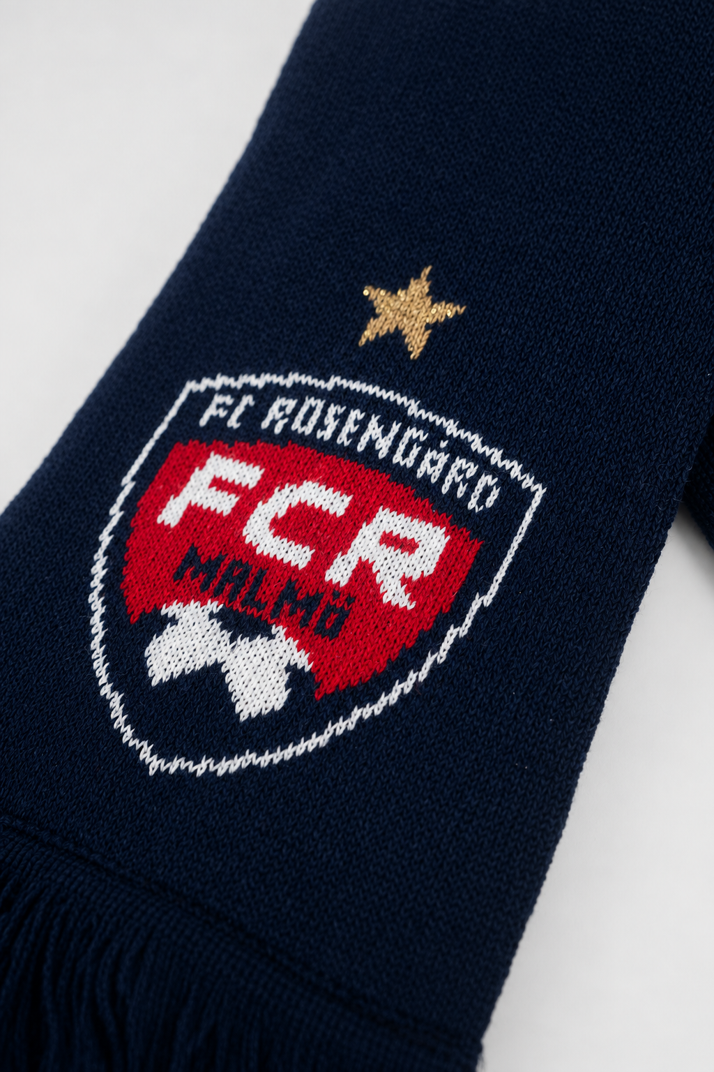 Studio-lit detail shot of the FC Rosengård crest woven into the navy scarf