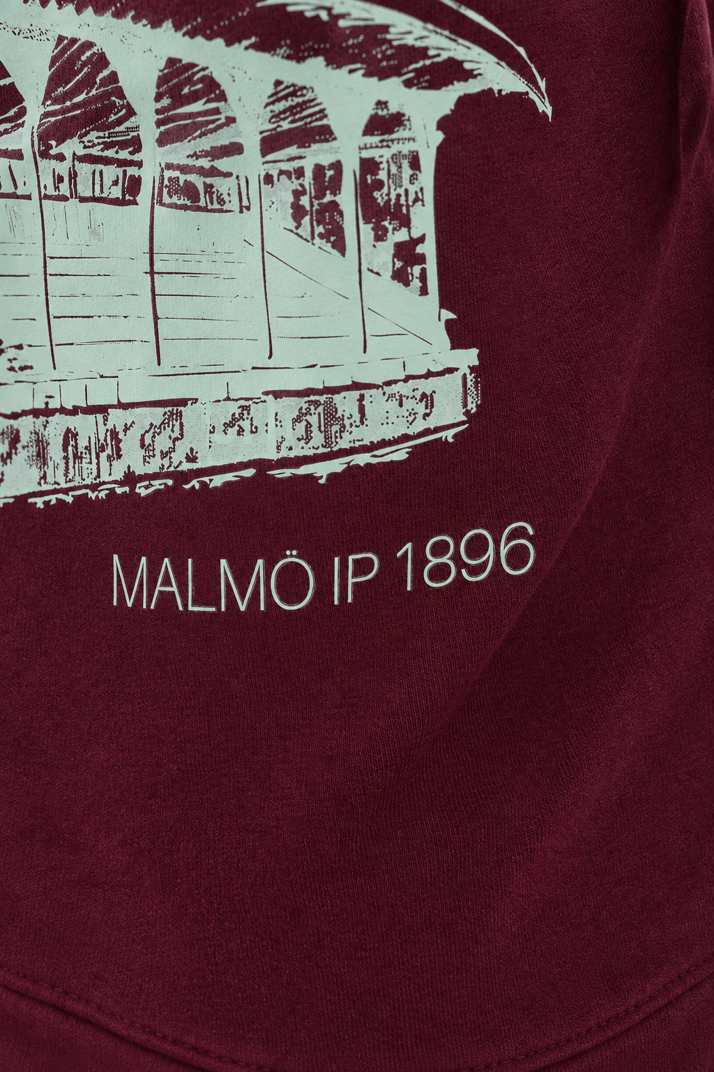 Studio-lit detail shot of the MALMÖ IP 1896 grandstand print on the burgundy hoodie